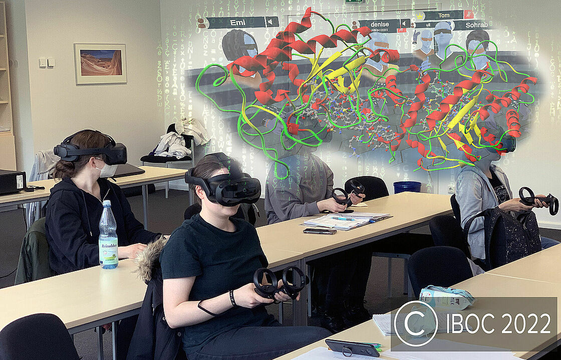 Bild zum VR-Projekt von Dr. Ulrich Krauß. Man sieht einen Seminarraum mit Studierenden, die VR-Brillen tragen. Über ihren Köpfen abgebildet ist die Struktur eines Enzyms, dargestellt durch bunte Bestandteile, sowie die Avatare der Student*innen, die das Enzym im virtuellen Raum erkunden.